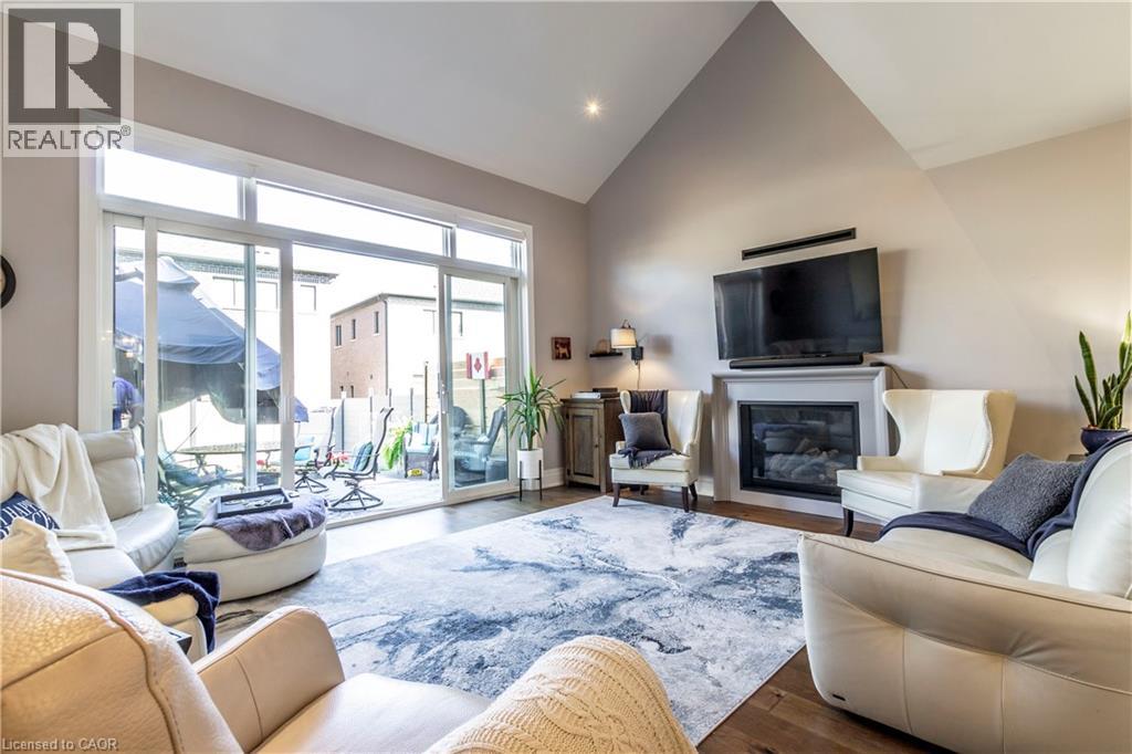 Living area featuring a glass covered fireplace, vaulted ceiling, and wood finished floors
