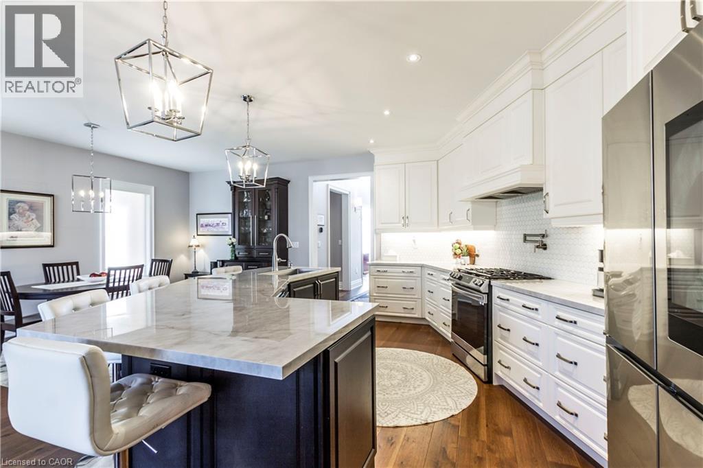 Two tone kitchen featuring stainless steel appliances, two tone color scheme, dark wood finished floors, light stone countertops, and a breakfast bar area