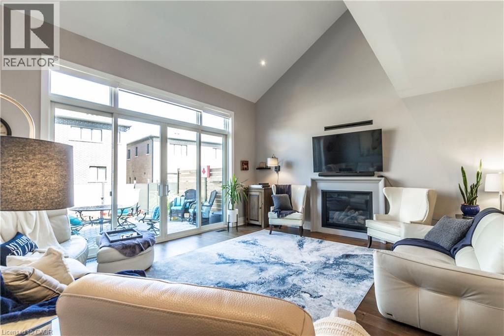 Living room with lofted ceiling, a glass covered fireplace, wood finished floors, and recessed lighting