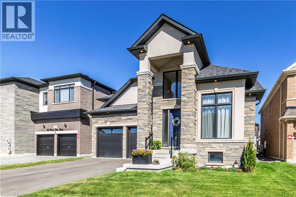 View of front of home with stone siding, a front lawn, and driveway