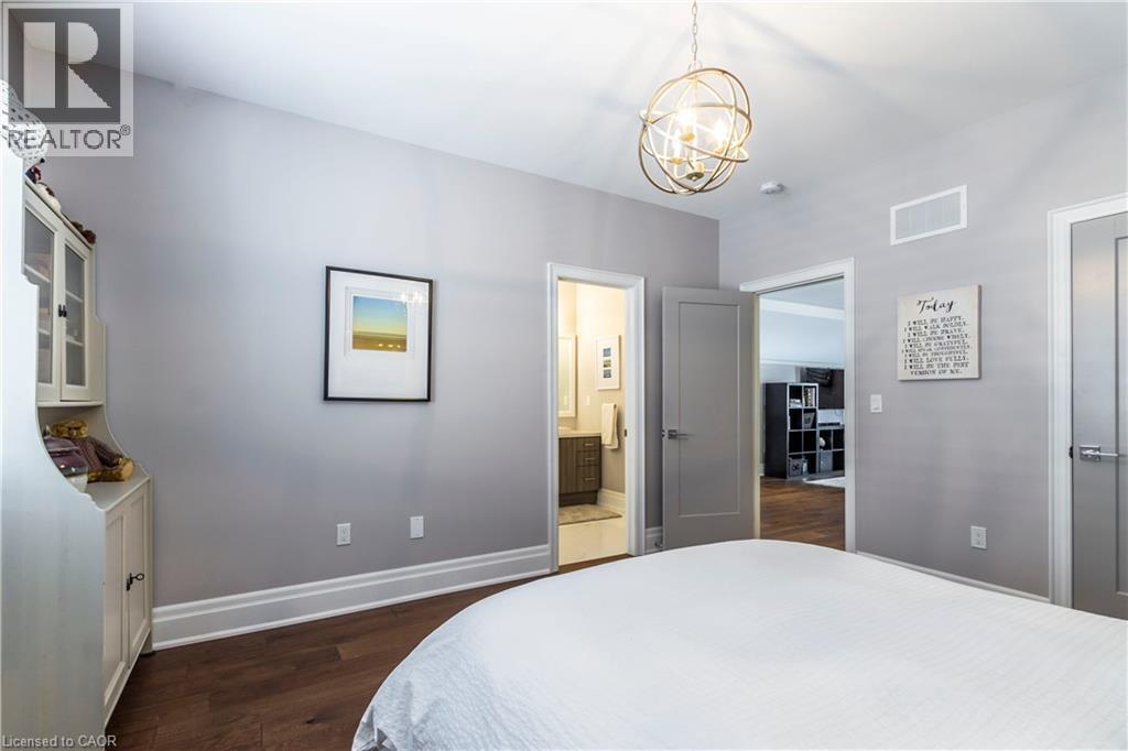 Bedroom with dark wood finished floors, a chandelier, and connected bathroom