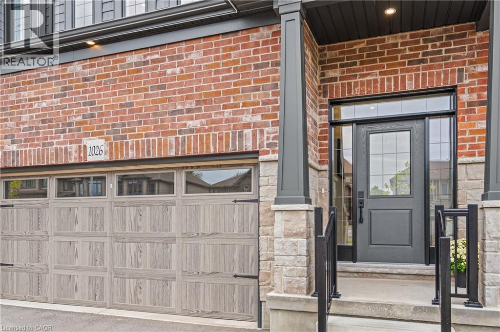 Brick and stone facade featuring a wood-finish garage door with upper windows and decorative hardware