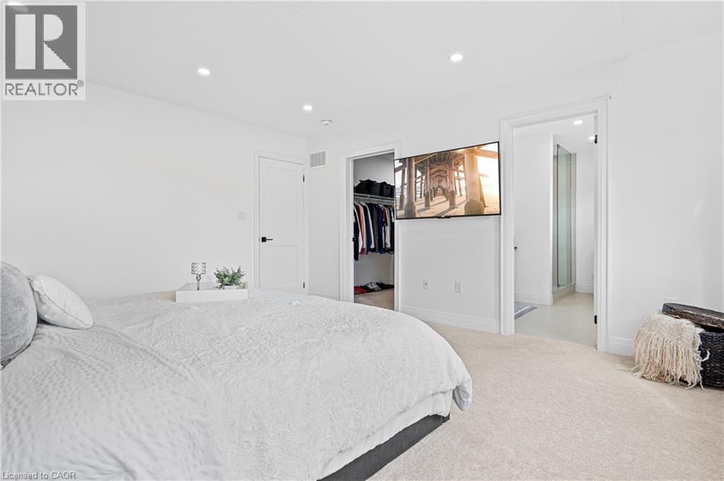 Bright bedroom with recessed lighting, light-toned carpeting, a built-in closet with shelving, and a wall-mounted television