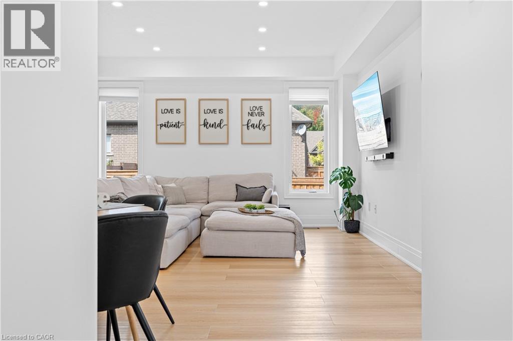 Bright open-concept living area featuring light wood-finish flooring, recessed lighting, and crisp white walls