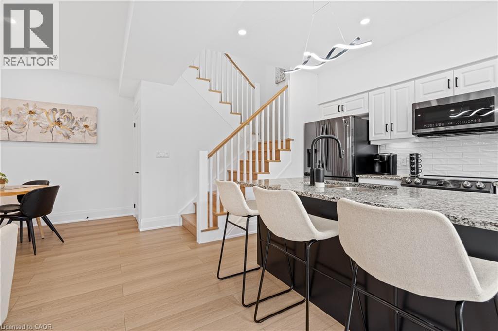 Kitchen island featuring a granite countertop, undermount sink with a matte black faucet, and seating for three