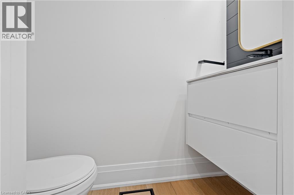 Modern powder room featuring a floating vanity with a white countertop, matte black wall-mounted faucet, and a contemporary mirror with a gold-tone frame