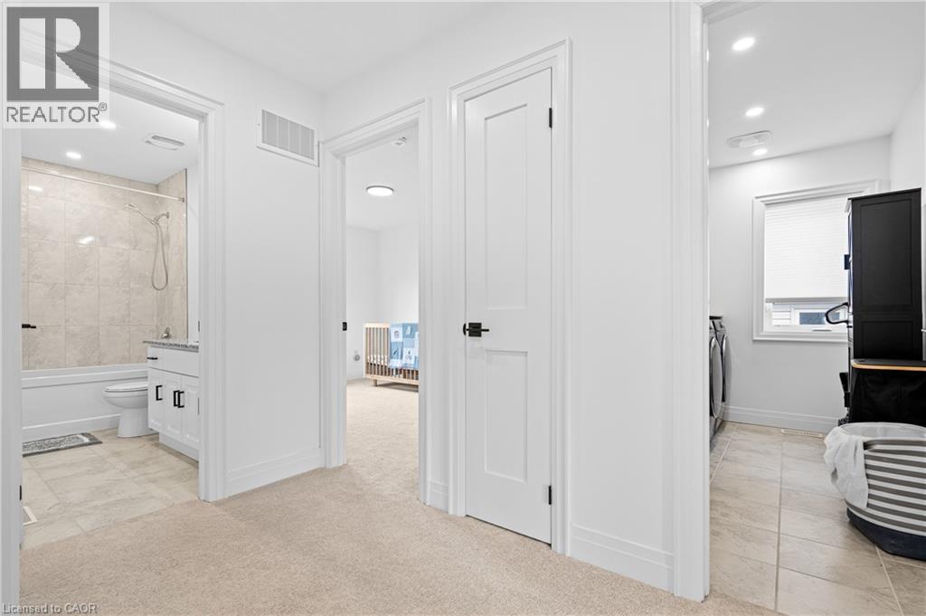 Carpeted hallway with white walls and recessed lighting