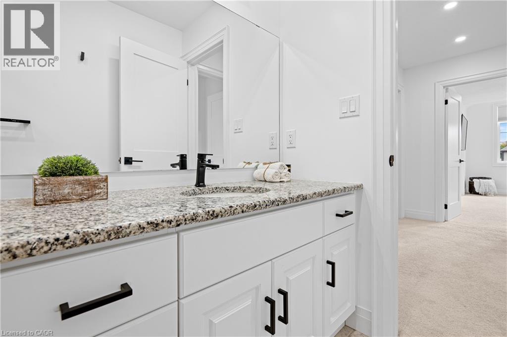 Double vanity with granite countertop, integrated sinks, white cabinetry, and matte black hardware