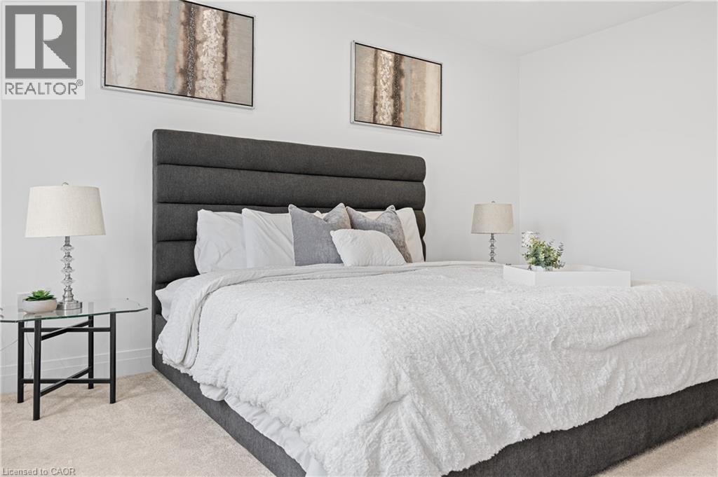 Spacious sleeping area featuring a tall, upholstered headboard, crisp white walls, and soft carpet flooring