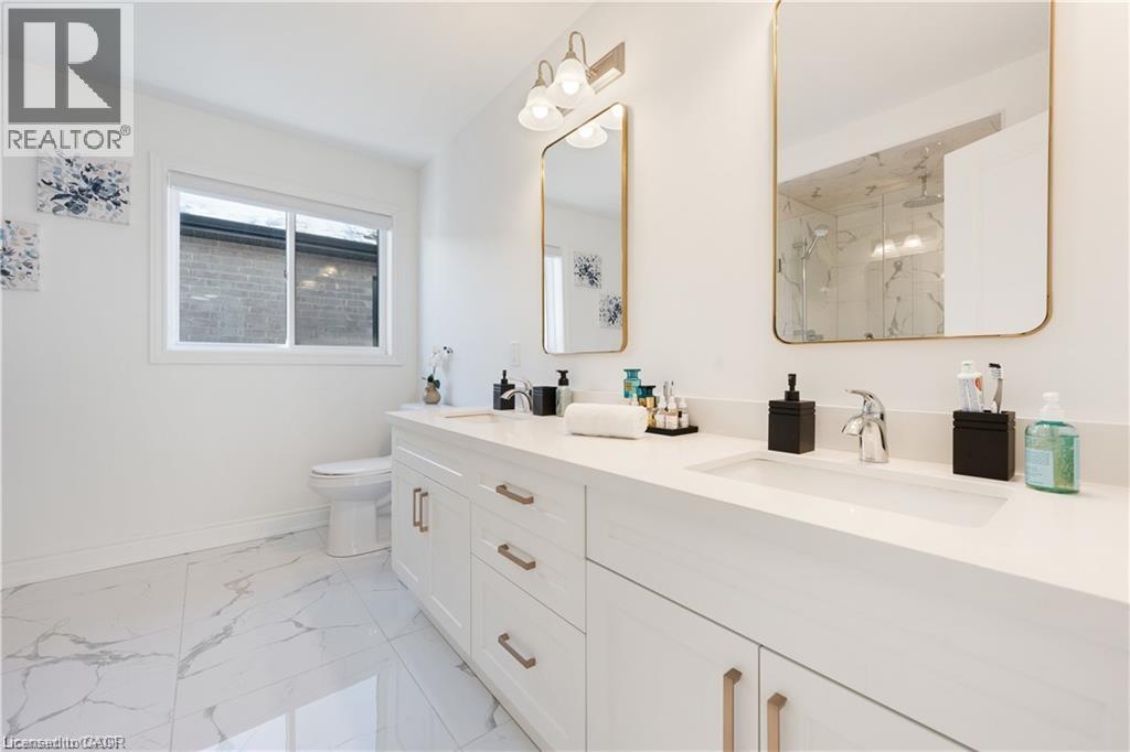 Full bathroom featuring a marble finish shower, double vanity, and light marble finish floors