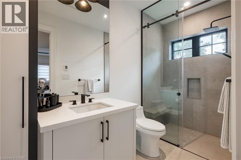 Bathroom featuring a white vanity with a rectangular sink, matte black fixtures, and a frameless glass shower enclosure