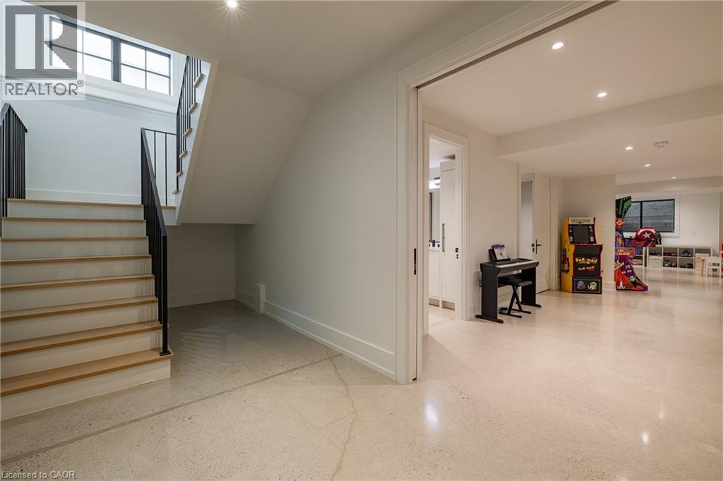 Lower level showcasing light-toned flooring, a staircase with wood-finish treads and black metal railing, and recessed lighting