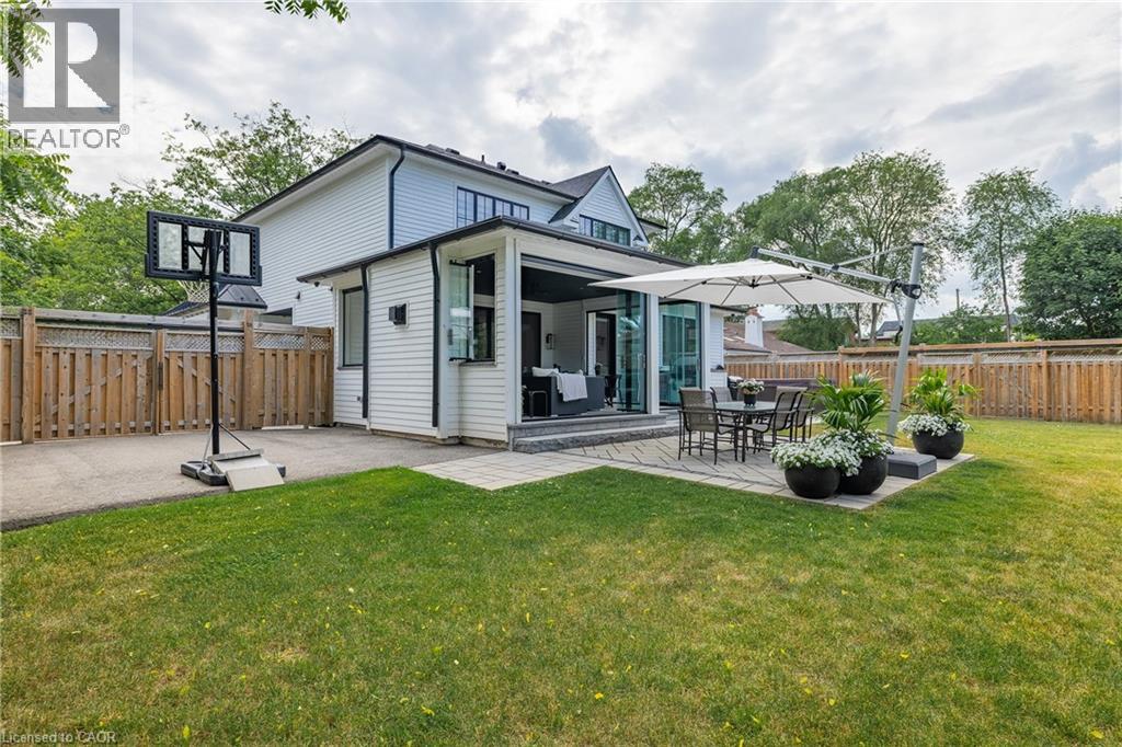 Expansive rear yard featuring a stone patio, manicured lawn, and privacy fencing