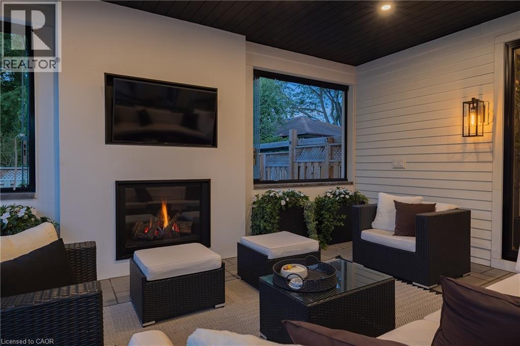 Covered patio featuring an integrated fireplace, wall-mounted television, exterior sconce lighting, and a dark wood-plank ceiling