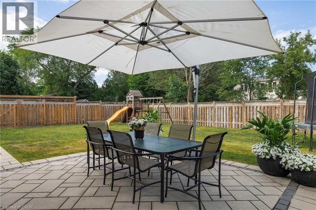 Spacious backyard featuring a patterned paver patio, lush green lawn, and a wooden privacy fence