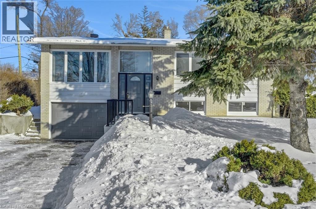 Split-level residence featuring a light brick facade and a dark gray garage door