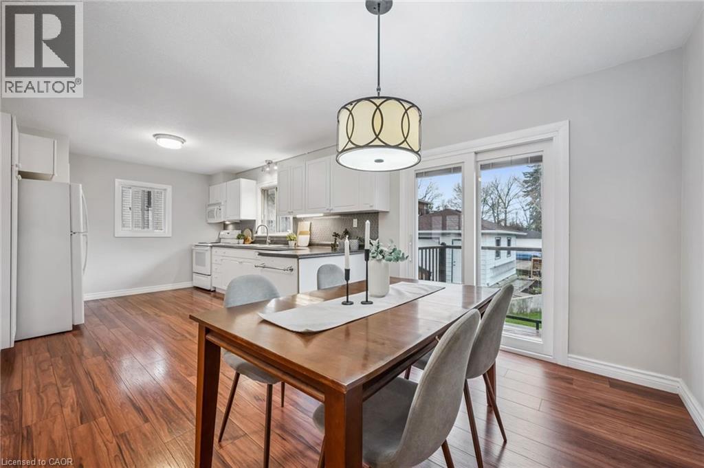 Open-concept dining area featuring wood-finish flooring and a contemporary pendant light fixture
