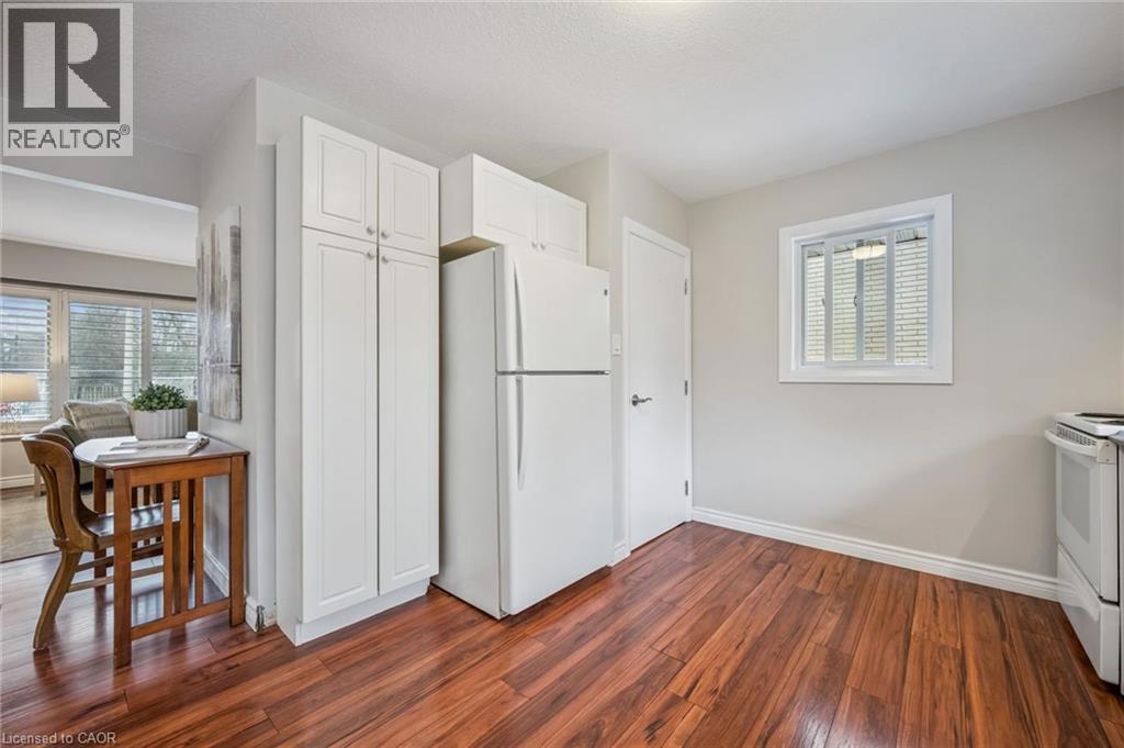 Kitchen area featuring wood-finish flooring, white cabinetry, and a white refrigerator