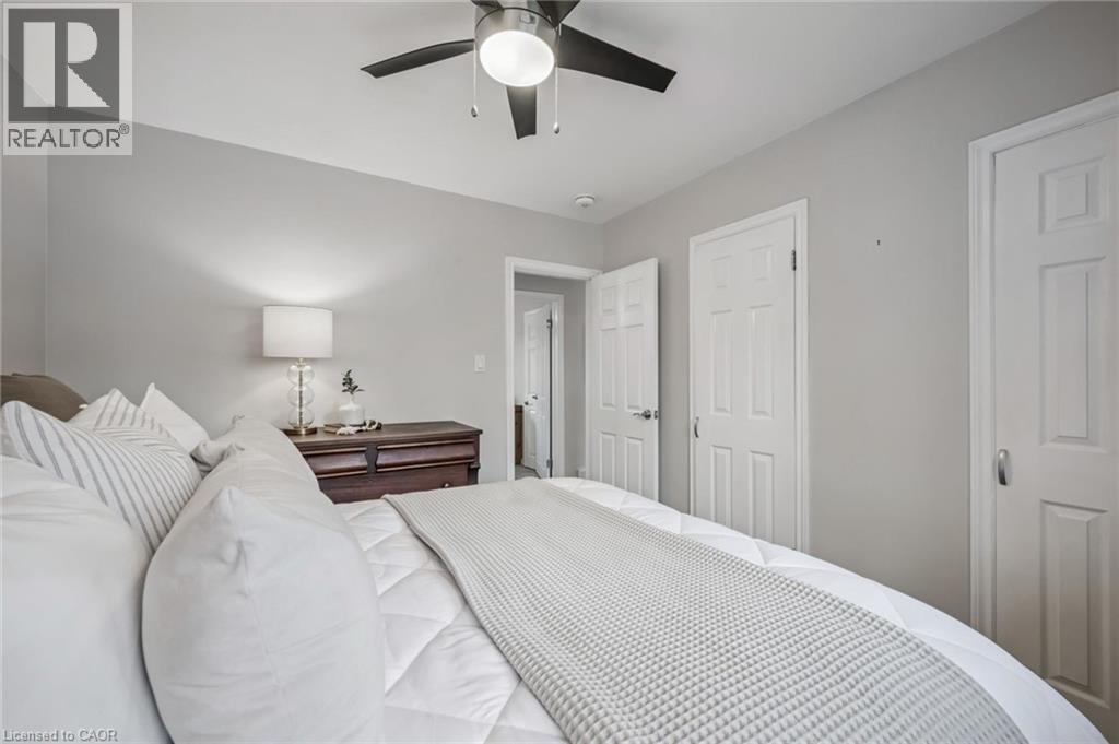 Recessed lighting and a ceiling fan fixture illuminate a room featuring light gray wall paint and white trim details