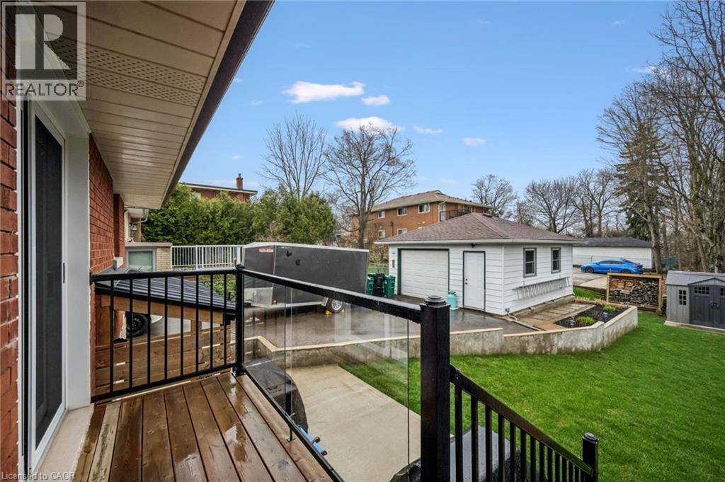 Spacious exterior featuring a wood-finish deck with glass panel railing, a detached garage with two bay doors, and a manicured lawn