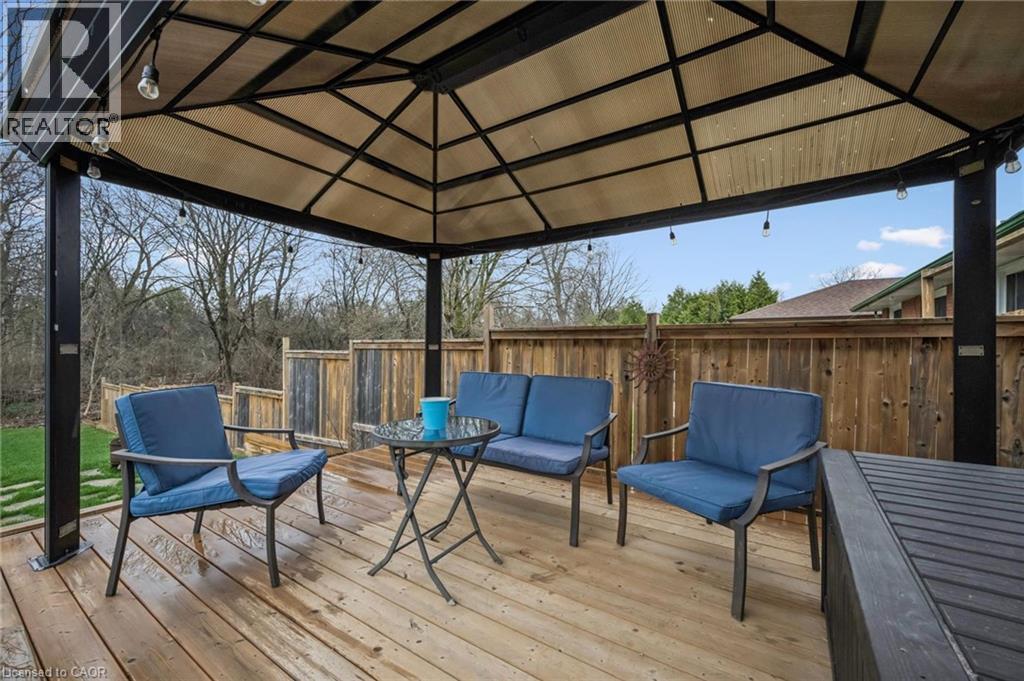 Wood-finish deck with a large gazebo featuring string lighting, complemented by a wood fence