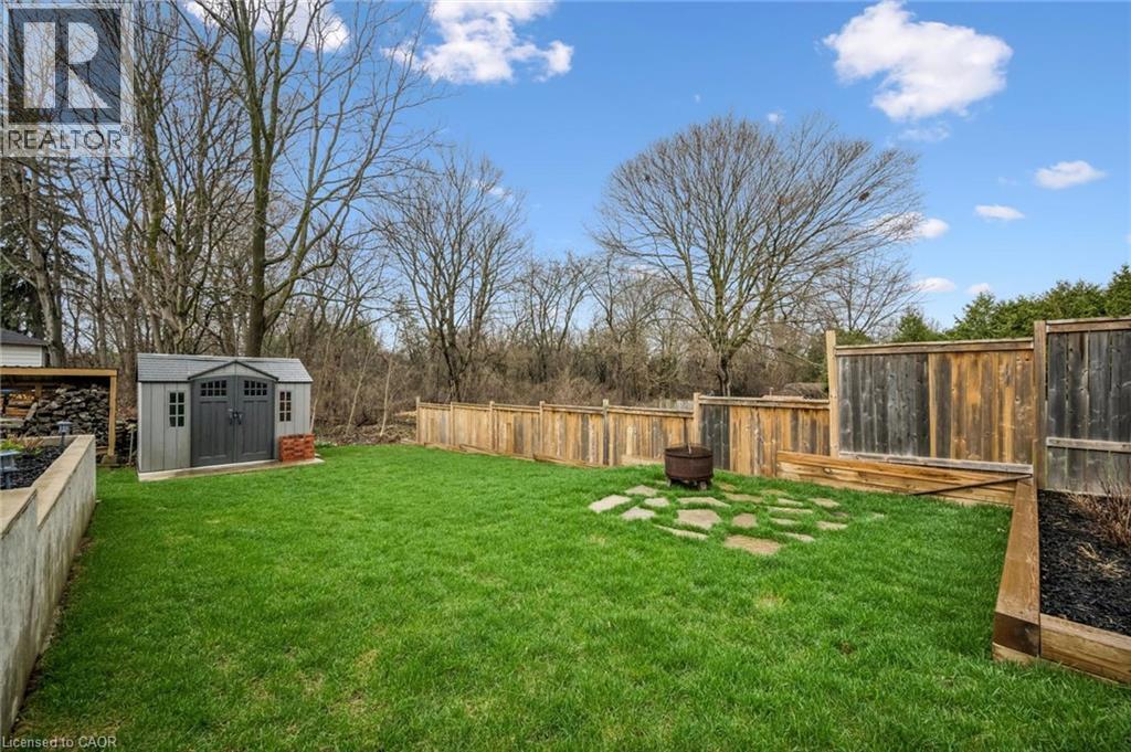 Expansive backyard featuring a manicured lawn, full wood fencing, and a dedicated storage shed
