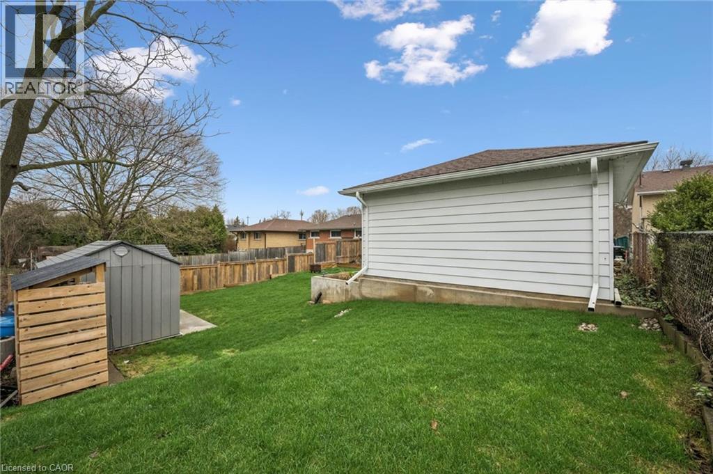 Expansive green space featuring a detached storage shed, privacy fencing, and a white siding structure
