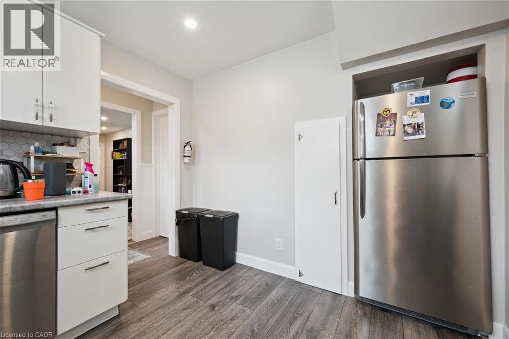 Kitchen featuring stainless steel appliances, white cabinetry, and wood-finish flooring