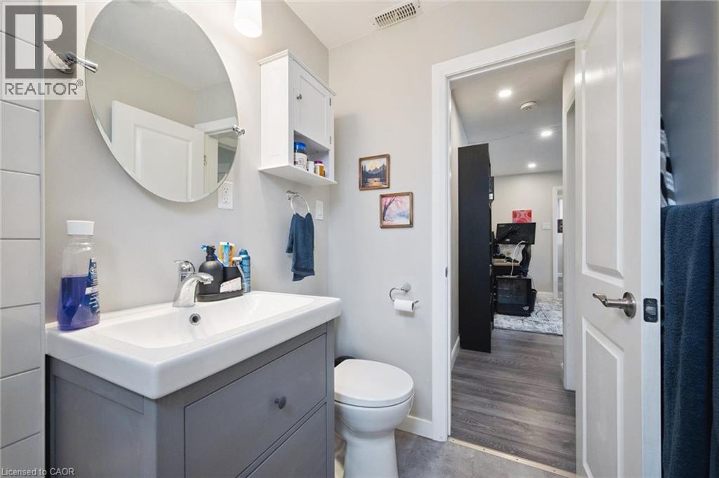 Bathroom featuring a gray vanity with an integrated sink, an oval mirror, and a wall-mounted storage cabinet