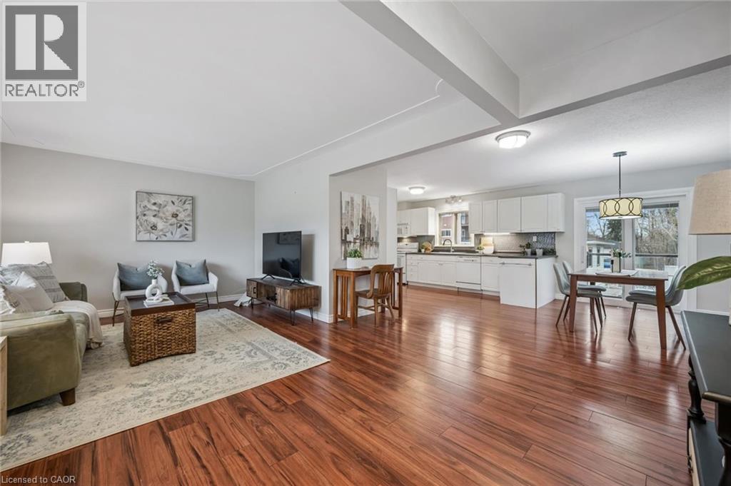 Open-concept living space featuring wood-finish flooring, recessed lighting, white kitchen cabinetry, and large windows