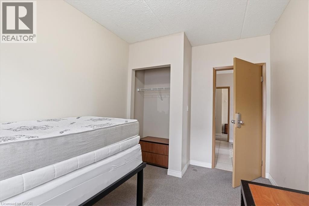 Room featuring light gray carpet flooring, an open closet with built-in shelving, a neutral wall color, and a textured white ceiling