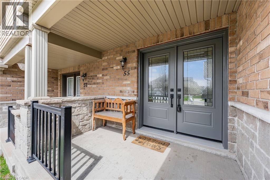 Front entrance featuring a double door with decorative glass inserts, brick facade, stone veneer accents, concrete porch, and a covered entry with columns