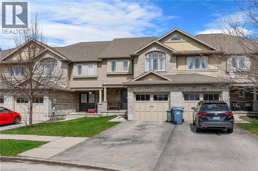 Multi-level townhouse exterior featuring a combination of brick and siding, multiple garage doors, and a covered front entry