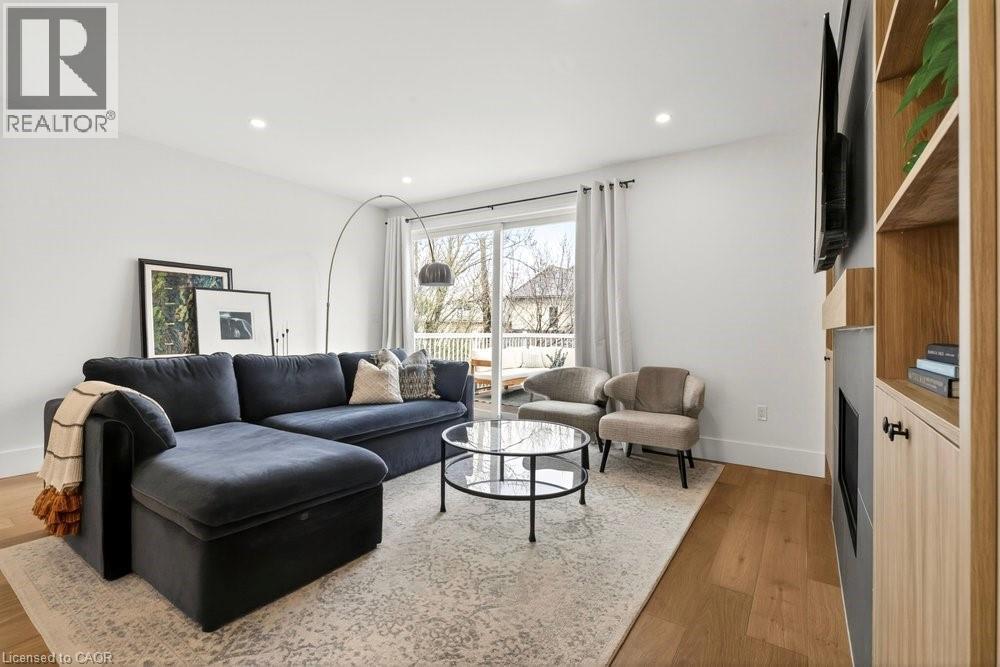 Bright living area featuring wood-finish flooring, recessed lighting, and a built-in entertainment center with open shelving