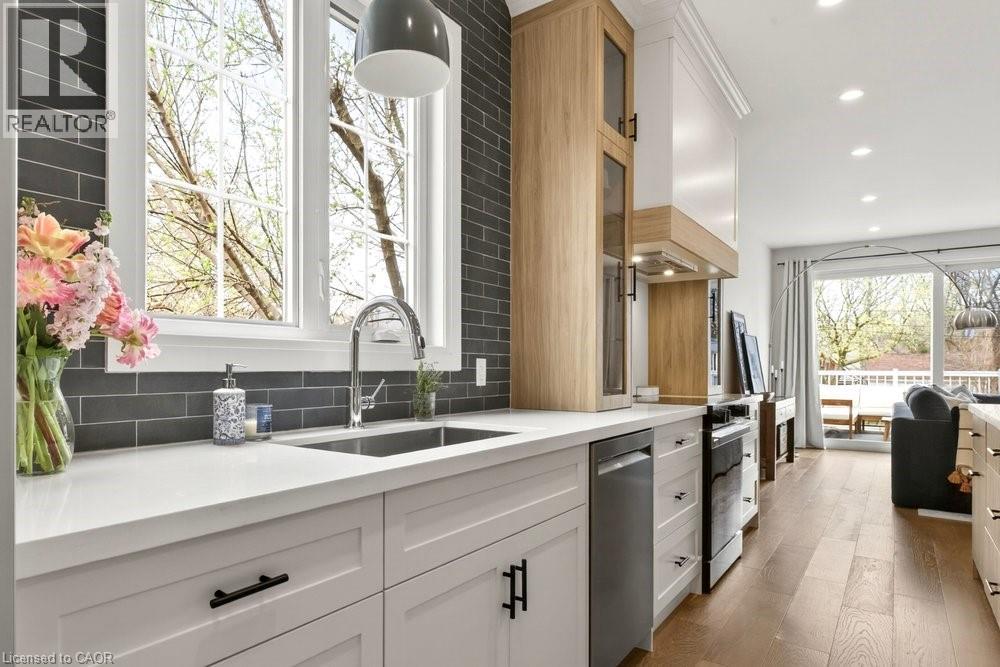 Bright kitchen featuring white shaker cabinetry, stainless steel sink, and light countertops