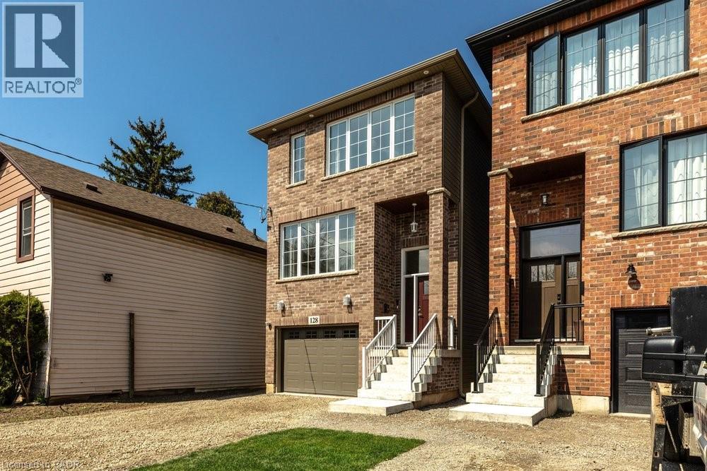 Brick exterior with multiple windows, an integrated garage, a covered entryway, and concrete steps with metal railings