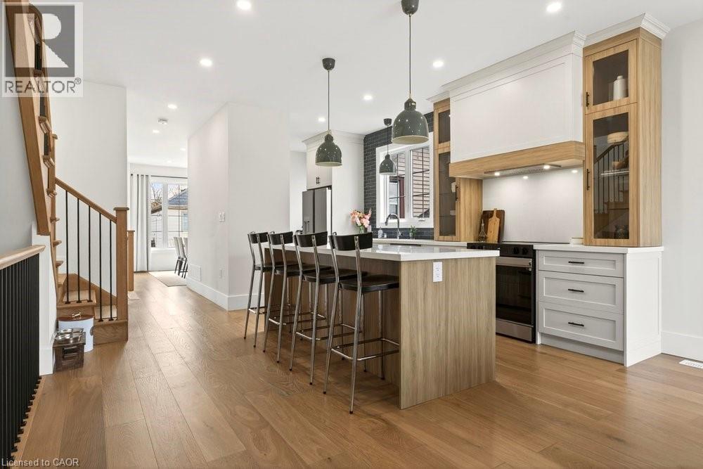Open-concept kitchen with wood-finish flooring, a central island featuring bar seating, pendant lighting, and stainless steel appliances