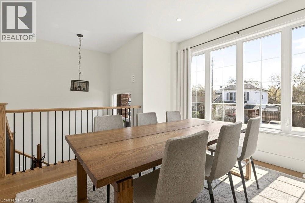 Bright dining area featuring expansive windows, wood-finish flooring, a contemporary pendant light fixture, and an open railing with metal balusters