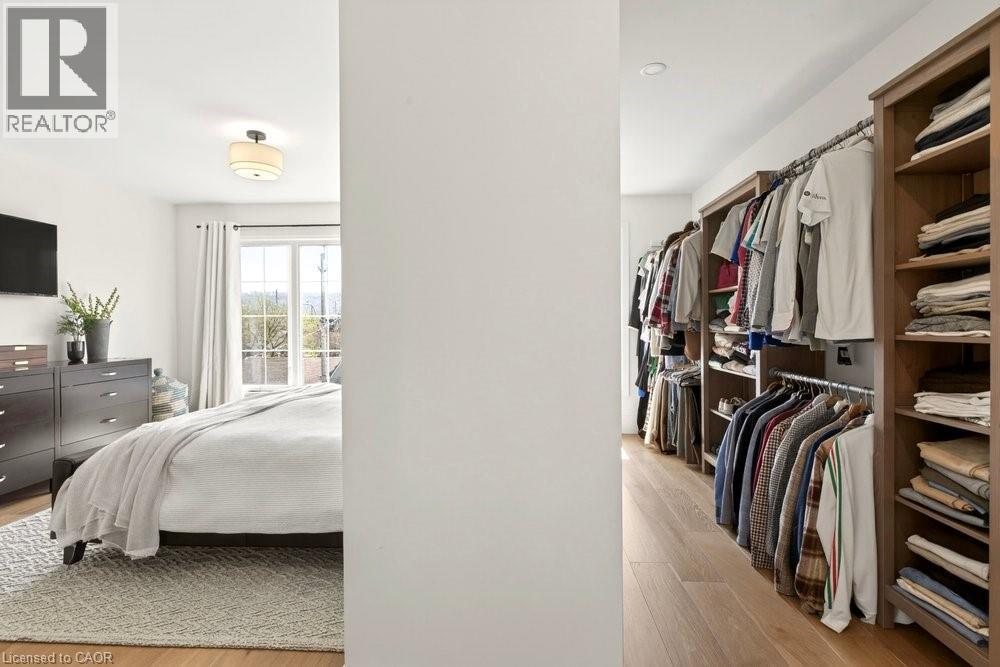 Bedroom with wood-finish flooring and a walk-in closet featuring custom wood shelving and hanging rods