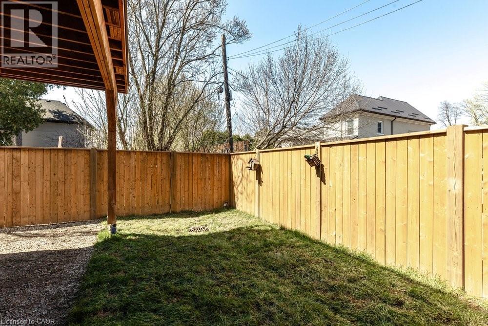 Fenced backyard featuring a gravel patio area and a grass lawn