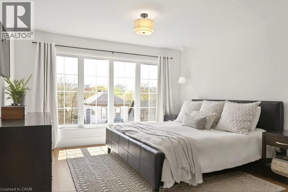 Hardwood flooring with a large window array, white walls, and a ceiling-mounted light fixture