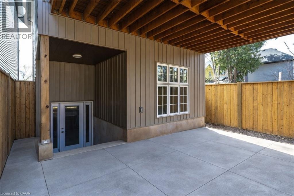 Covered concrete patio space featuring exposed wood joists and a privacy fence
