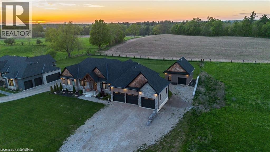 Contemporary stone and siding residence featuring multiple garages, a gravel driveway, and a detached auxiliary building
