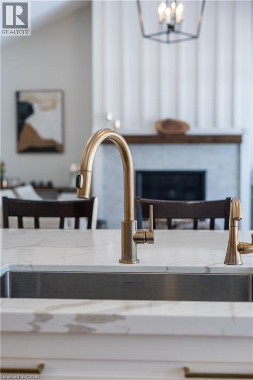 Kitchen island featuring an undermount stainless steel sink, a brushed gold high-arch faucet, and a white countertop with gray veining