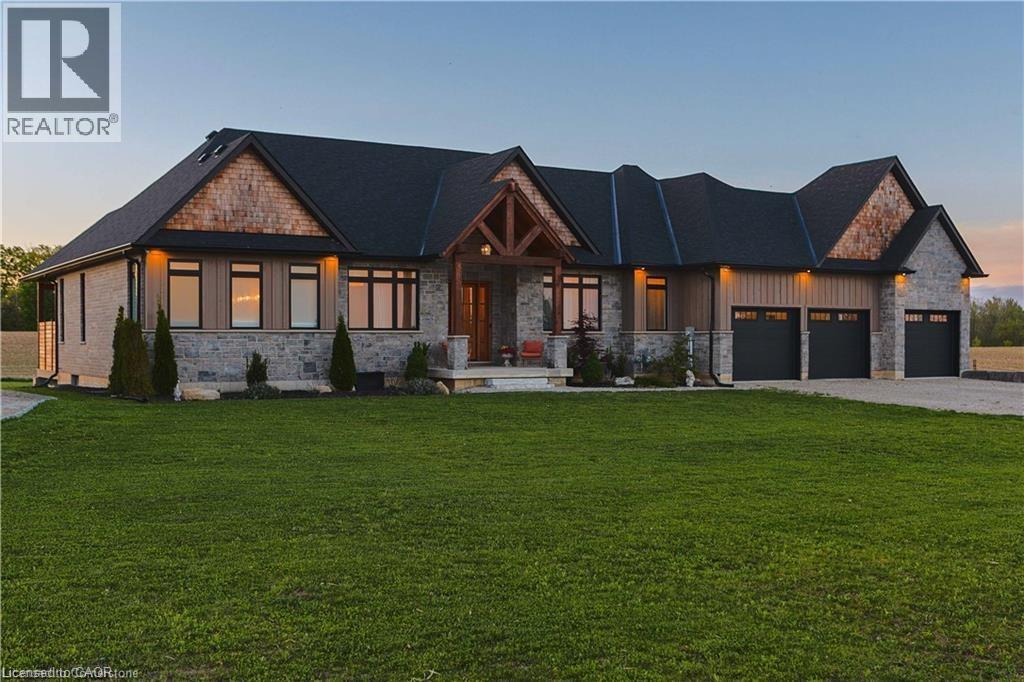 Stone and wood-sided ranch-style residence featuring a dark shingle roof and multiple gables