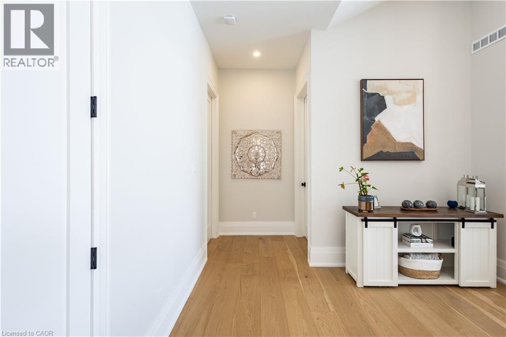 Hallway featuring light wood-finish flooring, white baseboards, recessed lighting, and a neutral wall palette