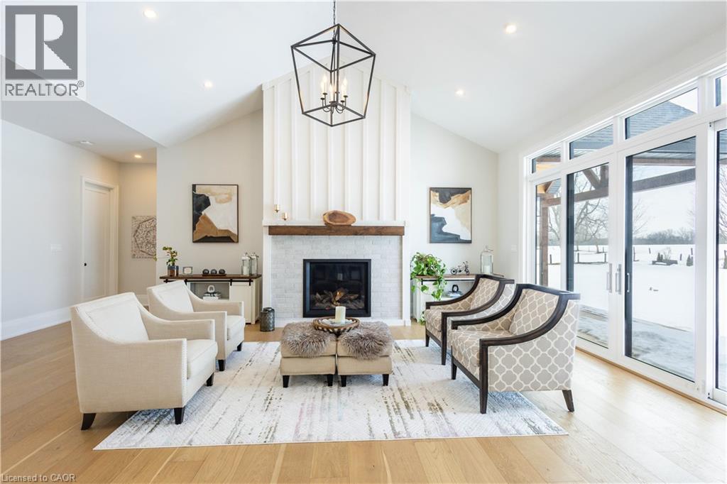 Spacious living area featuring a vaulted ceiling, wood-finish flooring, and a fireplace with a white tile surround