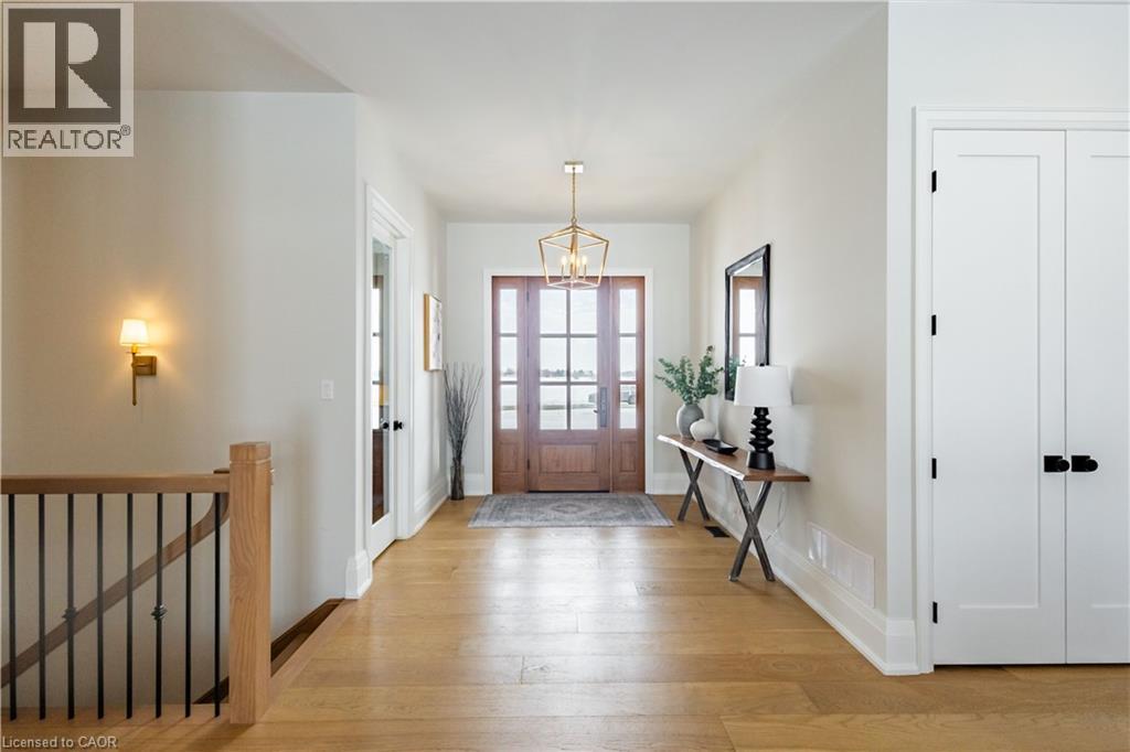 Light wood-finish flooring extending through an entry hall with a wooden front door featuring multiple glass panels
