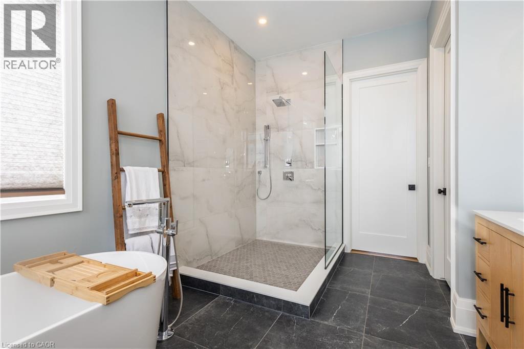 Spacious bathroom featuring a frameless glass shower enclosure with marble-finish wall tiling, a rainfall showerhead, and a tiled shower floor