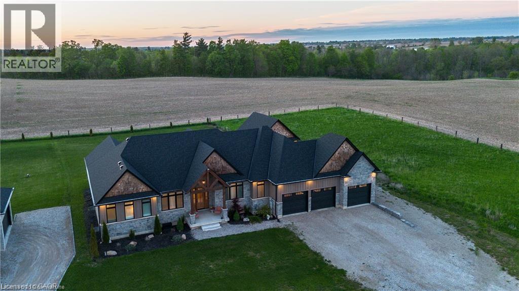 Ranch-style residence featuring a dark shingle roof, stone and horizontal siding exterior, and a three-car garage